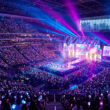 Vue panoramique d'un concert d'EXO avec une foule tenant des bâtons lumineux et une scène illuminée de néons.